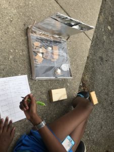 Youth participant logging observations while baking S'mores to test solar cooker.